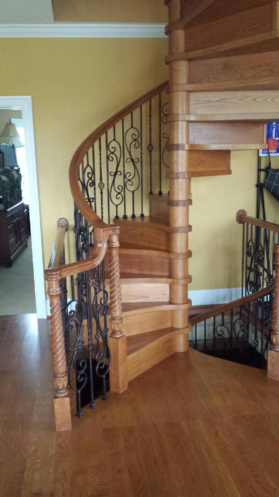 Spiral staircase with ornate iron balusters and rope-twist newel