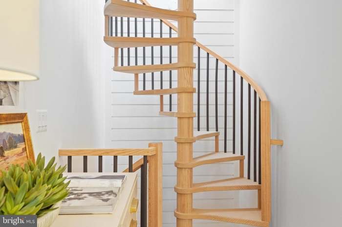 Spiral staircase with natural wood treads and black iron balusters
