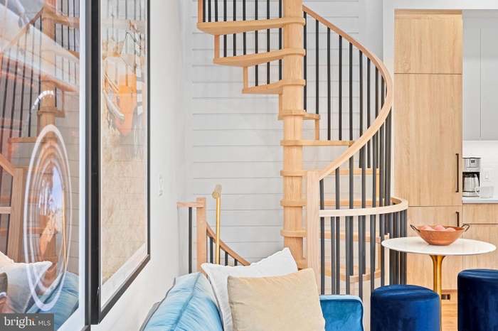 Spiral staircase with natural wood rail and black iron balusters — alternate view