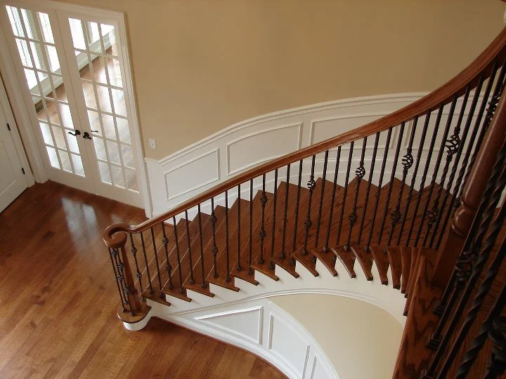 Curved staircase with metal balusters and wood rail